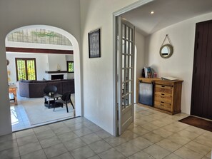 A modern interior with a dining area, kitchen, and a large arched doorway leading to another room. - Les Palmiers de Beauvallon House, rated 5 stars, sleeps 6, with a pool (Grimaud)