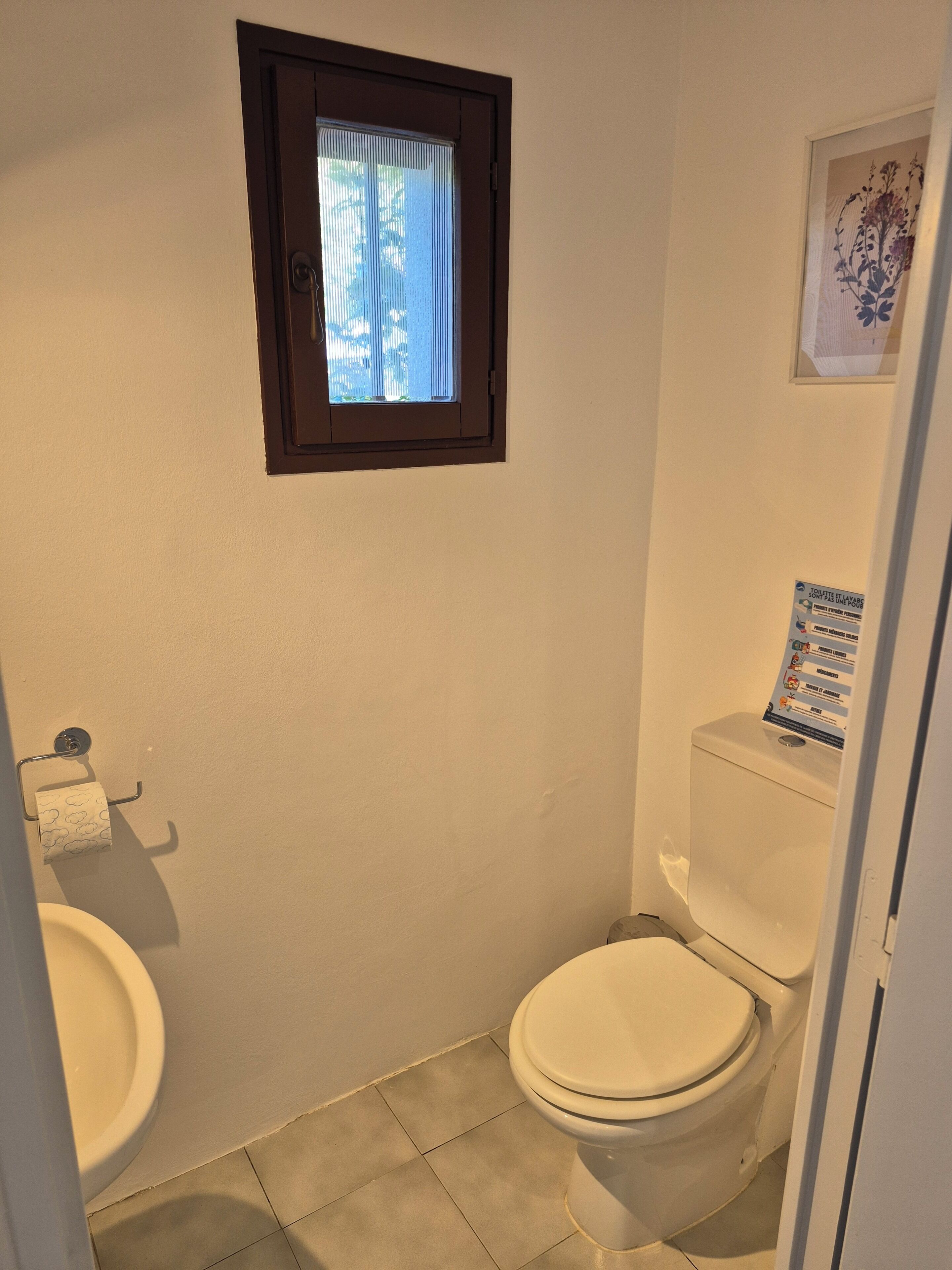 Ein kleines Badezimmer mit Toilette, Waschbecken und Fenster.