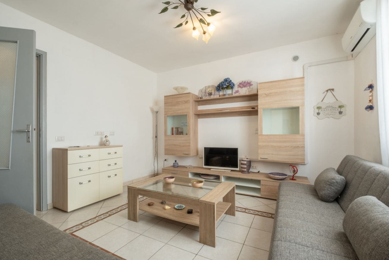 Un salon moderne comprenant un canapé, une table basse, un téléviseur et des étagères intégrées.