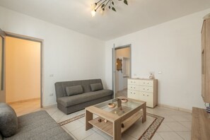 Un soggiorno moderno con un divano, un tavolino in vetro, un mobile contenitore e un tappeto decorato.