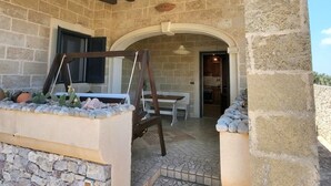 Un edificio in pietra con travi a vista in legno, una panca e un tavolo.