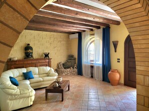 A cozy living room with a sofa, a coffee table, and a decorative Buddha statue. - Country villa with a private pool, grove, and large garden, 1 km from the sea (Corsano)