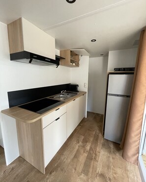 A modern kitchen with a built-in stove, sink, and a refrigerator. - New bungalow at a 3-star campground—right on the water (Porto-Vecchio)