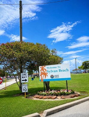 A welcome sign for Sylvan Beach with a one-way direction sign and a speed limit sign.