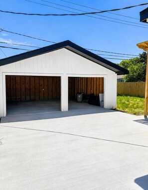 A single-story building with a garage and a covered outdoor area. - Home: 3 Minutes to Sylvan Beach with a Hot Tub and Office Space (La Porte)