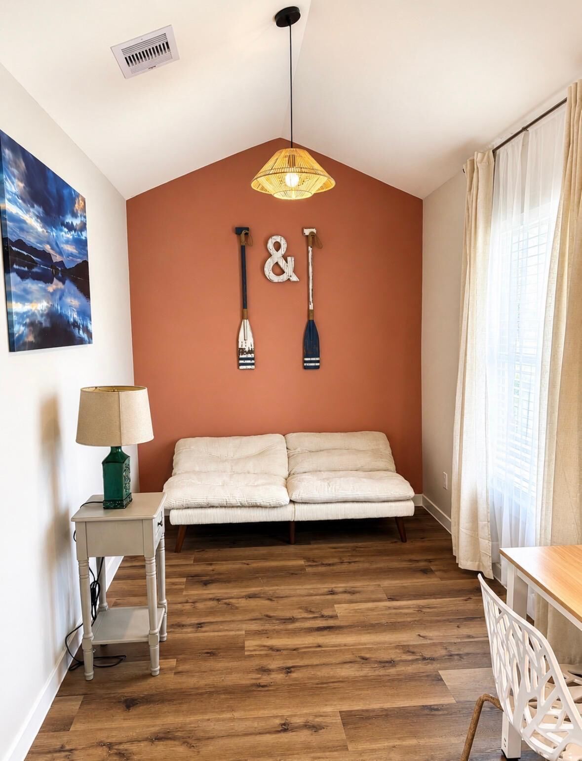 A room with a bed, a lamp, a painting, and two paddleboards on the wall.