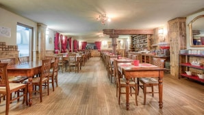A dining hall with multiple wooden tables and chairs, a long counter, and a variety of kitchenware displayed on shelves. - Hotel Mon Reve (Valtournenche)