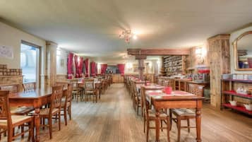 Un comedor con varias mesas y sillas de madera, una larga barra y una variedad de utensilios de cocina exhibidos en estantes.