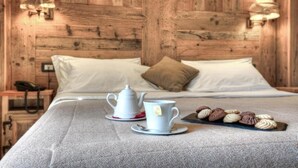 A bed with white linens, a bedside table with a telephone, a tea set, and a tray of cookies. - Hotel Mon Reve (Valtournenche)