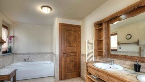 A bathroom with a bathtub, two sinks, wooden vanity, and a large mirror. - Hotel Mon Reve (Valtournenche)