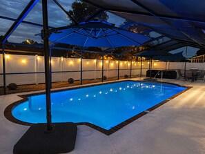 A swimming pool with a blue tint, surrounded by a covered patio area with a ceiling structure. - Heated Saltwater Pool, Game Room&Mini Golf. Near Anna Maria Island & IMG Academy (Bradenton)