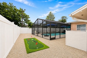 A backyard with a pool, a covered patio, and a mini-golf setup. - Heated Saltwater Pool, Game Room&Mini Golf. Near Anna Maria Island & IMG Academy (Bradenton)