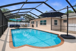 A swimming pool with a covered area, a patio with seating, and a house in the background. - Heated Saltwater Pool, Game Room&Mini Golf. Near Anna Maria Island & IMG Academy (Bradenton)
