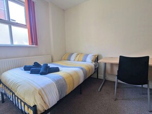 A single bed with a striped blanket, a small table, a chair, and a window with curtains. - Spacious 5-Bed House in Sheffield City Centre (Sheffield)