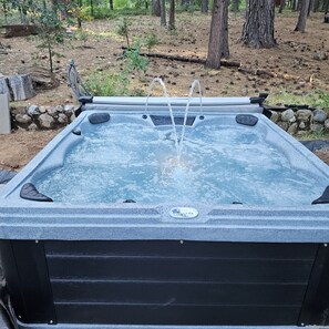 A hot tub with a stone wall and trees in the background. - ​Peaceful 3BR Arnold Escape w/ Hot Tub, AC & Deck. Steps from Arnold Rim Trail (Arnold)