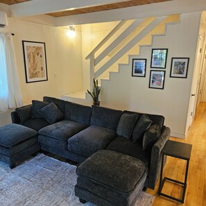 A living room with a sectional sofa, a small ottoman, a coffee table, a staircase, and framed pictures on the wall. - ​Peaceful 3BR Arnold Escape w/ Hot Tub, AC & Deck. Steps from Arnold Rim Trail (Arnold)