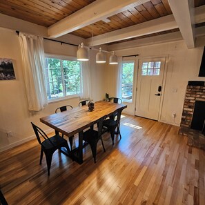A dining area with a wooden table, black chairs, and a view of the outdoors through a window. - ​Peaceful 3BR Arnold Escape w/ Hot Tub, AC & Deck. Steps from Arnold Rim Trail (Arnold)