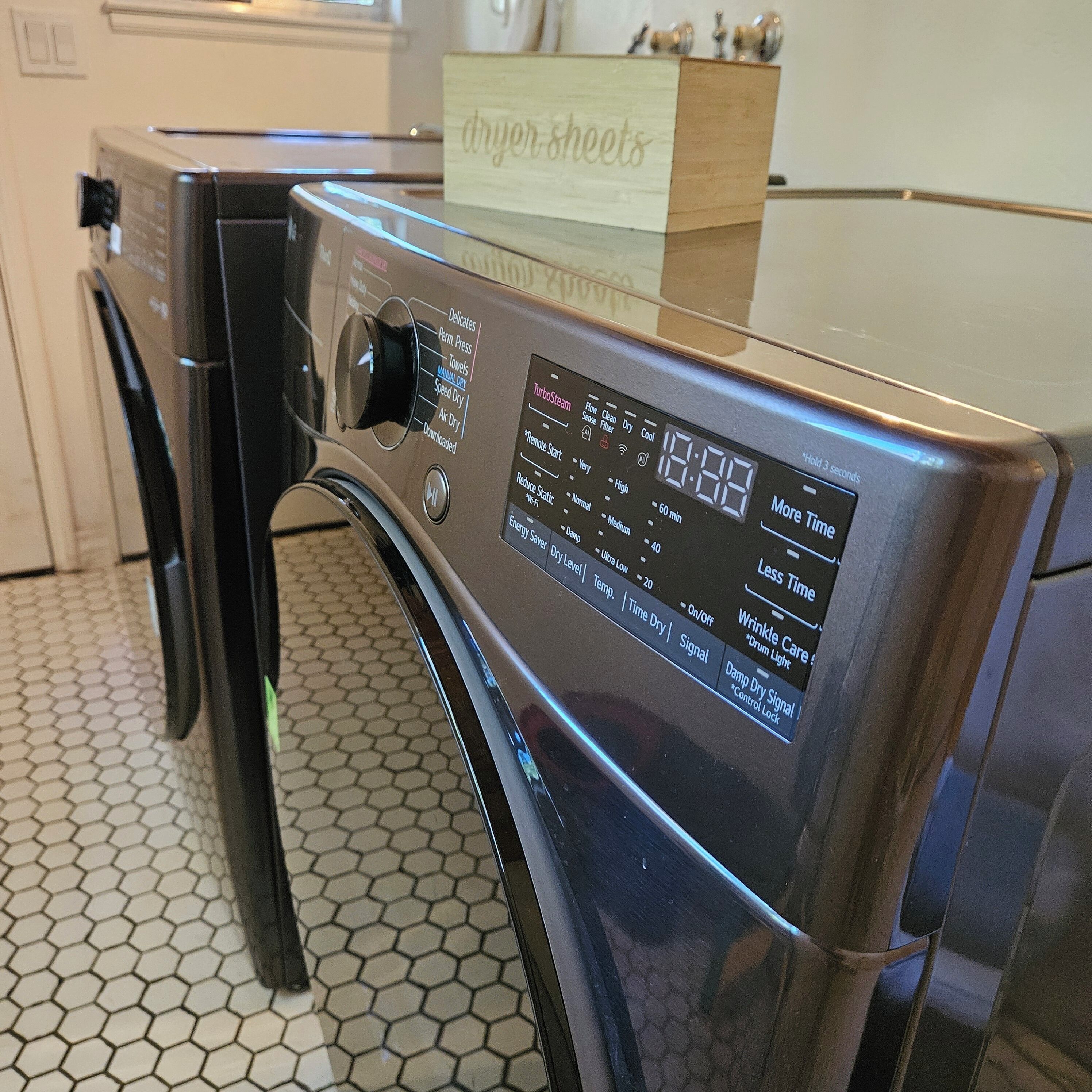 A front view of a modern, stainless steel front-loading washer and dryer unit with a digital display and control panel.