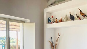 A modern living room with a sliding glass door leading to an outdoor area, a flat-screen TV, and decorative bird figurines on shelves. - Dune (Montalto di Castro)