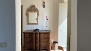 A room with a wooden dresser, a mirror, and a door leading to another room. - Dune (Montalto di Castro)