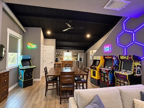 A room with a dining table, chairs, arcade games, and a ceiling fan. - Texas sized family fun with basketball, pickleball, gym, arcade, billiards etc.. (Anna)