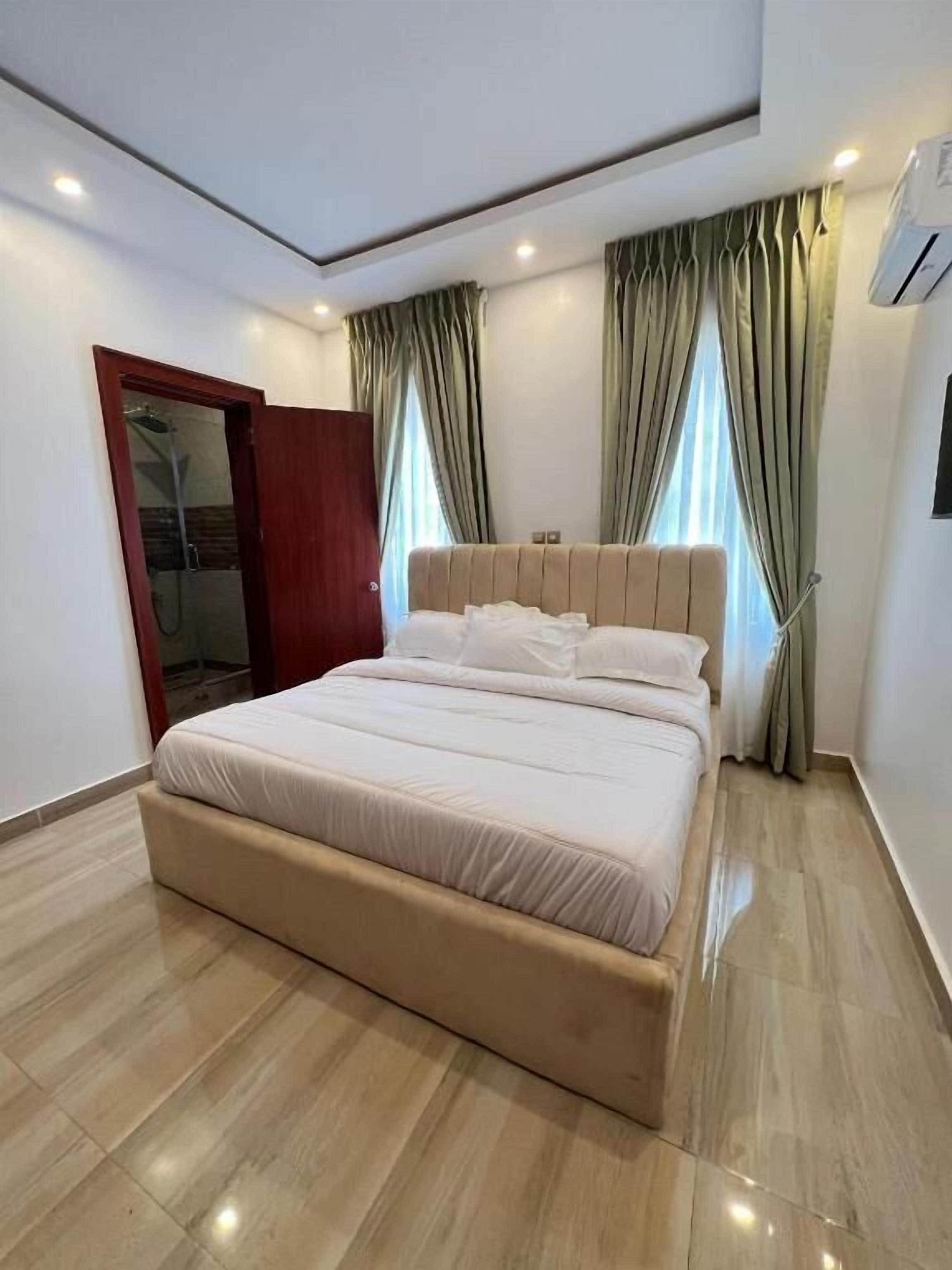 Quarto moderno com cama grande, guarda-roupa e espaço para chuveiro.