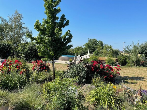 Un jardin agrémenté de diverses plantes et fleurs, un banc en bois et une structure en pierre.