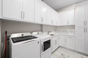 A laundry room with a washing machine, dryer, and a sink. - Wonderful 4-bedroom house with AC in tranquil Cape Coral (Cape Coral)
