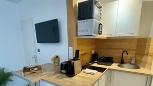 Una cocina compacta con encimera de madera, horno integrado, cafetera y lavabo.