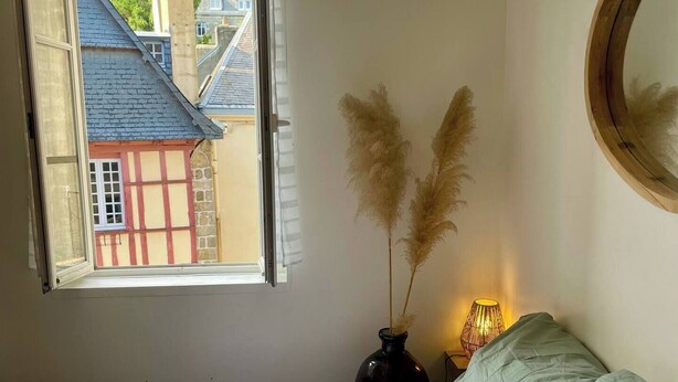 Un dormitorio con cama, ventana, lámpara de noche y espejo.