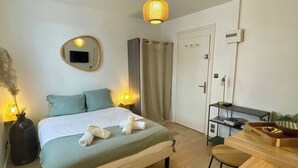 Un dormitorio con cama, lámparas de noche, un espejo, un armario y una pequeña mesa de madera.
