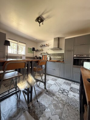 A kitchen with a dining area, a ceiling fan, and patterned floor tiles. - Villa (90-square-meter home) (Fréjus)