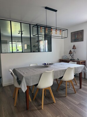 A dining area with a long table, white chairs, and a modern chandelier. - Villa (90-square-meter home) (Fréjus)