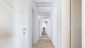 Een gang met aan beide kanten witte deuren, een gestreept plafond en een vloerkleed.