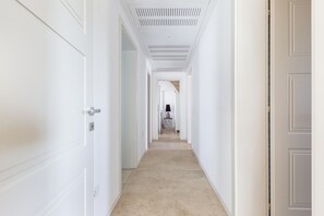 Ein Flur mit weißen Türen an beiden Seiten, einer gemusterten Decke und einem Teppichboden.
