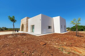 A modern, single-story building with a stone archway entrance, a flat roof, and a small window. - Onirica Dimora by BarbarHouse (Salve)