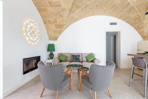 A living room with a fireplace, a sofa with green cushions, two patterned chairs, and a table with a lamp. - Onirica Dimora by BarbarHouse (Salve)