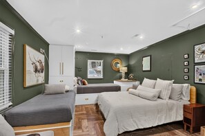 A bedroom with a bed, a bedside table, a mirror, and a window with blinds. - Pool Oasis Near SI Beach | Walk to Parks + Dining (Mount Pleasant)