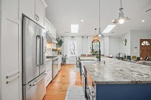 A modern kitchen with stainless steel appliances, a marble island, and pendant lighting. - Pool Oasis Near SI Beach | Walk to Parks + Dining (Mount Pleasant)