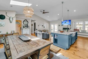 A spacious kitchen with a large island, wooden flooring, and a ceiling fan. - Pool Oasis Near SI Beach | Walk to Parks + Dining (Mount Pleasant)