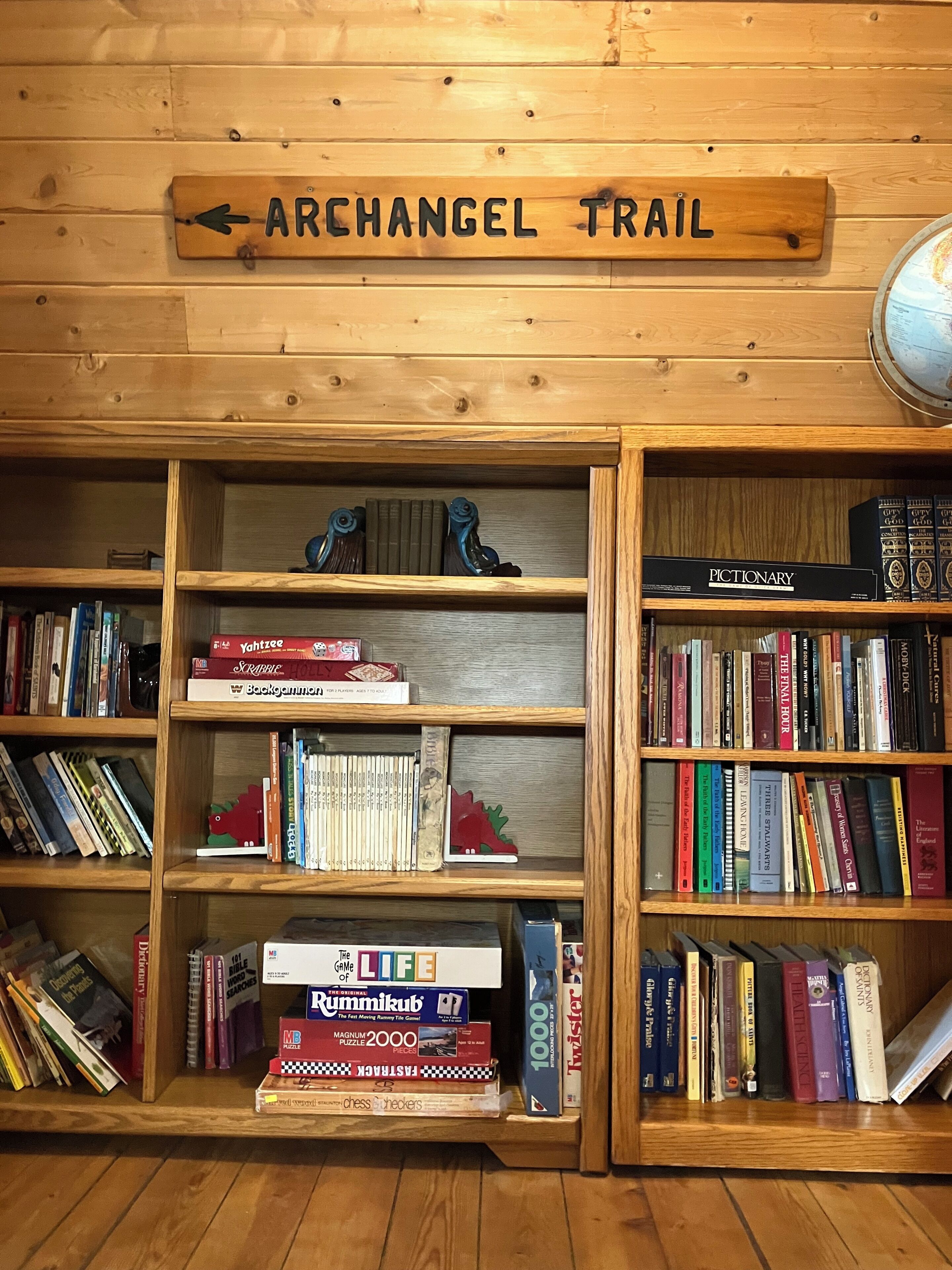 A wooden bookshelf with books and a sign above it that reads 'ARCHANGEL TRAIL'.