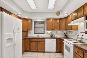 A modern kitchen with wooden cabinets, a built-in dishwasher, a stove, and a refrigerator. - Gold King House: Hot Tub, Pool Table. Near Peak 10 (Breckenridge)