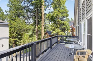 A wooden deck with a table and chairs, surrounded by trees and a building. - Gold King House: Hot Tub, Pool Table. Near Peak 10 (Breckenridge)