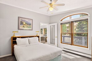 A bedroom with a bed, a ceiling fan, a framed picture, and a large window with a view of the outdoors. - Gold King House: Hot Tub, Pool Table. Near Peak 10 (Breckenridge)