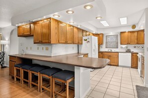 A modern kitchen with wooden cabinets, a central island with bar stools, and built-in appliances. - Gold King House: Hot Tub, Pool Table. Near Peak 10 (Breckenridge)