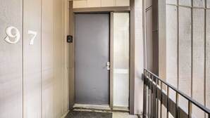 A narrow hallway with a door marked '97' and a metal railing on the right. - NEW - Charming 2-Bedroom Condo Near Shuttle Stops and Downtown (Breckenridge)