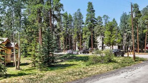 A residential area with a wooden cabin, a paved road, and several vehicles parked along the street. - NEW - Charming 2-Bedroom Condo Near Shuttle Stops and Downtown (Breckenridge)
