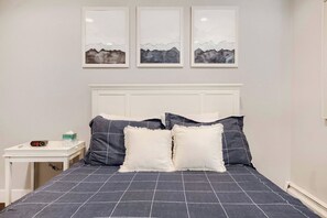 A bedroom with a bed, pillows, a bedside table, a clock, and three framed pictures on the wall. - NEW - Charming 2-Bedroom Condo Near Shuttle Stops and Downtown (Breckenridge)