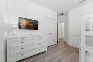 A hallway with a white dresser, a flat-screen TV mounted above it, and a door leading to another room. - House 12Q with Pool with Heating - and Game Room (Kissimmee)