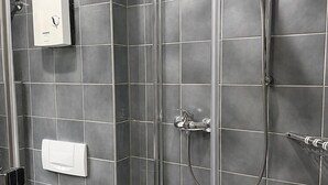 A modern bathroom with a glass-enclosed shower, a toilet, and a towel rack.